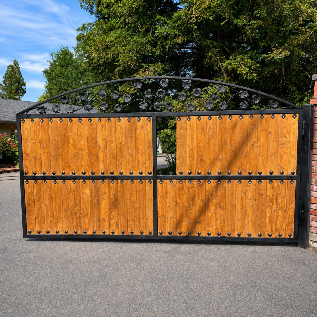 Arched wood gate with black iron frame and forged floral scrollwork