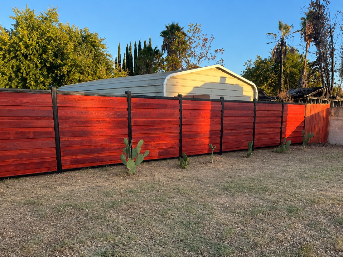 Stained horizontal wood privacy fence with black steel posts
